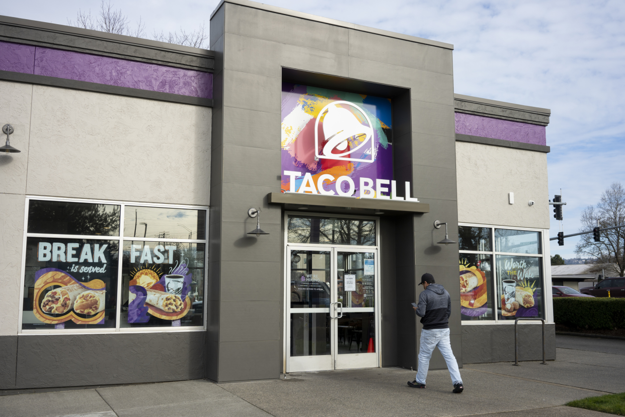 Front Exterior of Taco Bell Restaurant, Portland, Oregon, modern architecture dark and light grey with bright purple, man is walking towards the front doors on a winter early evening