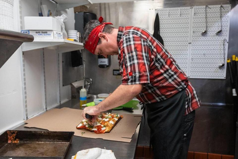Matty Evans, chef of Rise Up! Pizza, slices a completed Detroit-style pizza from within the kitchen of the restaurant’s new location within Horse & Jockey Pub on Cheapside.