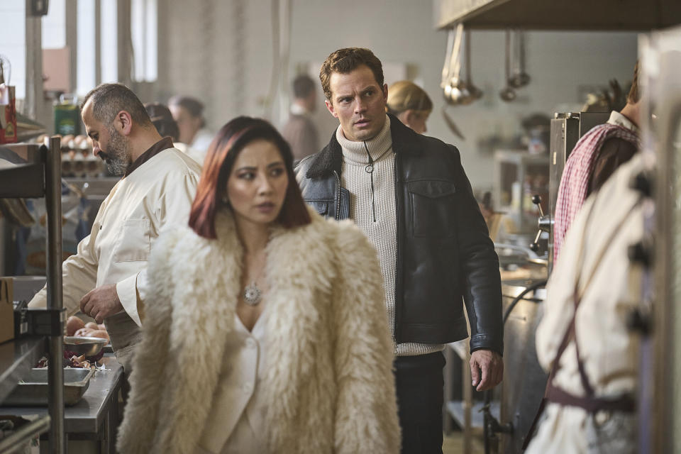 This image released by Netflix shows Jing Lusi and Jamie Dornan, background center, in a scene from "Heart of Stone." (Robert Viglasky/Netflix via AP)