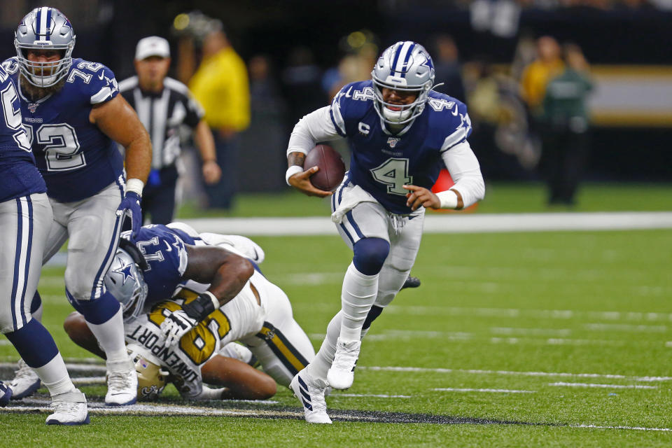 Dallas Cowboys quarterback Dak Prescott (4) scrambles as New Orleans Saints defensive end Marcus Davenport (92) is shoved to the turf by Cowboys offensive tackle Tyron Smith (77) in the first half of an NFL football game in New Orleans, Sunday, Sept. 29, 2019. (AP Photo/Butch Dill)