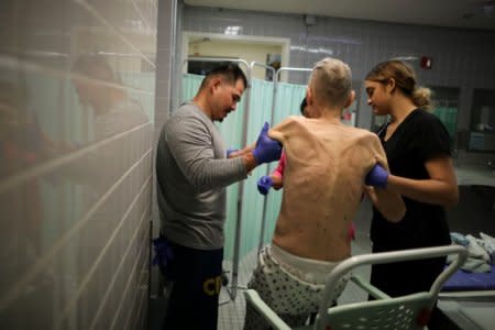 Pastoral Care Services Worker and inmate Kao Saephanh (L) helps inmate Joseph Morrow, 69, who has bladder cancer, take a shower in the hospice at the California Medical Facility prison in Vacaville, California, U.S., May 22, 2018.  REUTERS/Lucy Nicholson