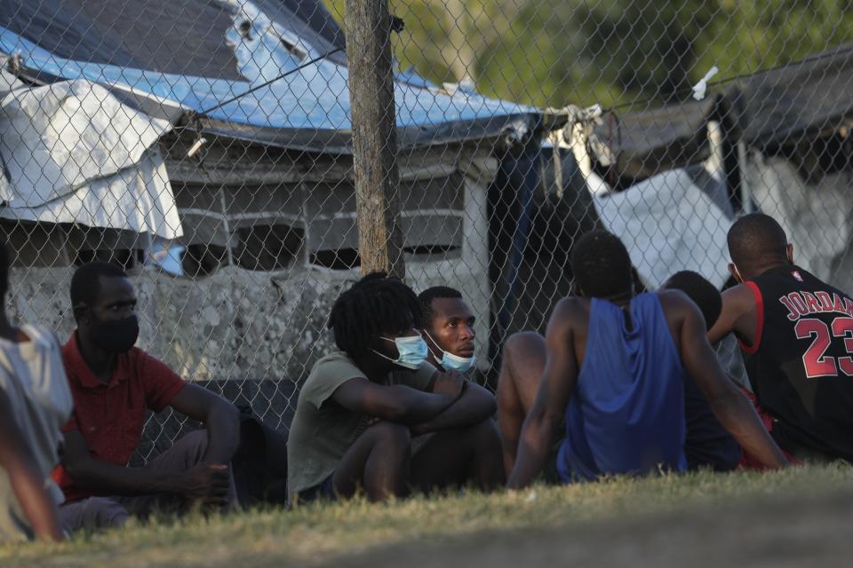 Haitian migrants sit on the grass at a migrant camp amid the new coronavirus pandemic in San Vicente, Darien province, Panama, Tuesday, Feb. 9, 2021. Panama is allowing hundreds of migrants stranded because of the pandemic, to move to the border with Costa Rica, after just reopening its land borders. (AP Photo/Arnulfo Franco)