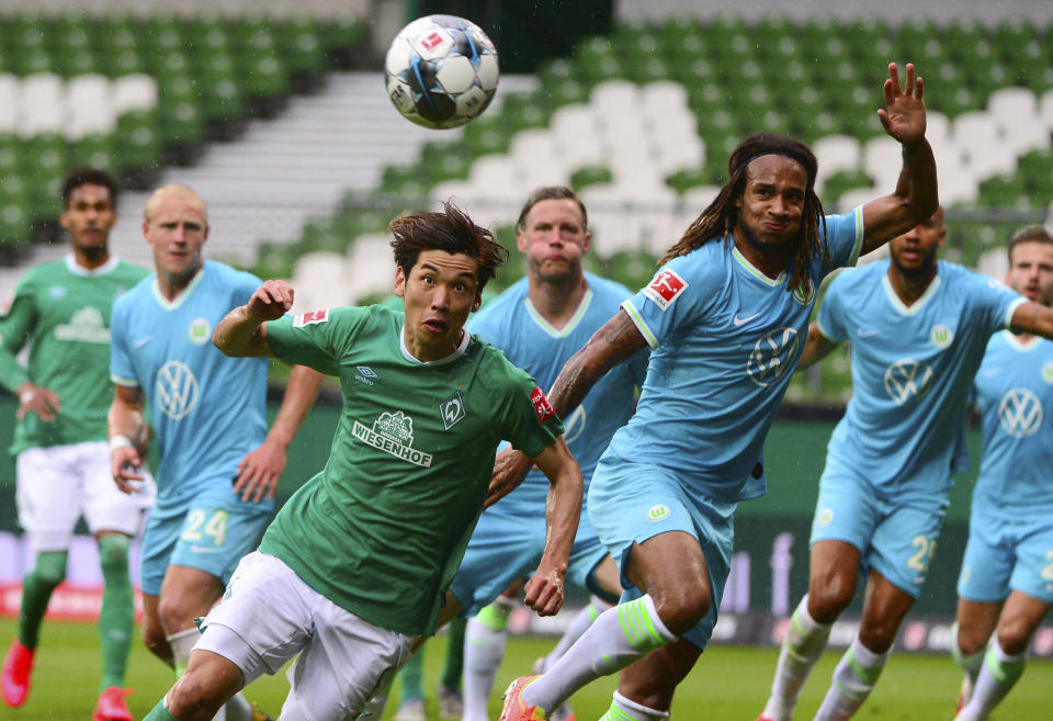 Bremen's Japanese forward Yuya Osako (L) and Wolfsburg's Swiss defender Kevin Mbabu vie for the ball during the German Bundesliga soccer match between Werder Bremen and VfL Wolfsburg in Bremen, Germany, Sunday, June 7, 2020. (Patrik Stollarz, Pool via AP)