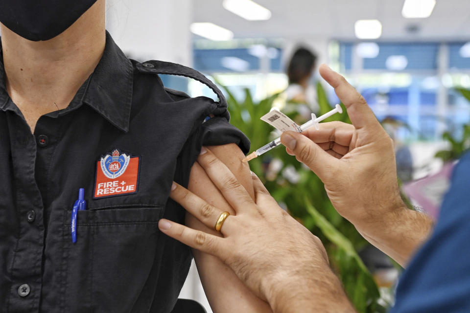 FILE - In this May 10, 2021, file photo, a Fire and Rescue worker receives a Pfizer vaccine at the newly opened COVID-19 vaccination center in Sydney, Australia. Some wealthy nations that were most praised last year for controlling the coronavirus are now lagging far behind in getting their people vaccinated — and some, especially in Asia, are seeing COVID-19 cases grow. (Nick Moir/Pool Photo via AP, File)