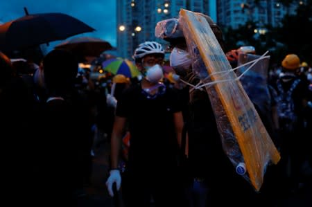 Anti-extradition bill protester holds a shield made from a sign board near riot police after a march at Sha Tin District of East New Territories, Hong Kong