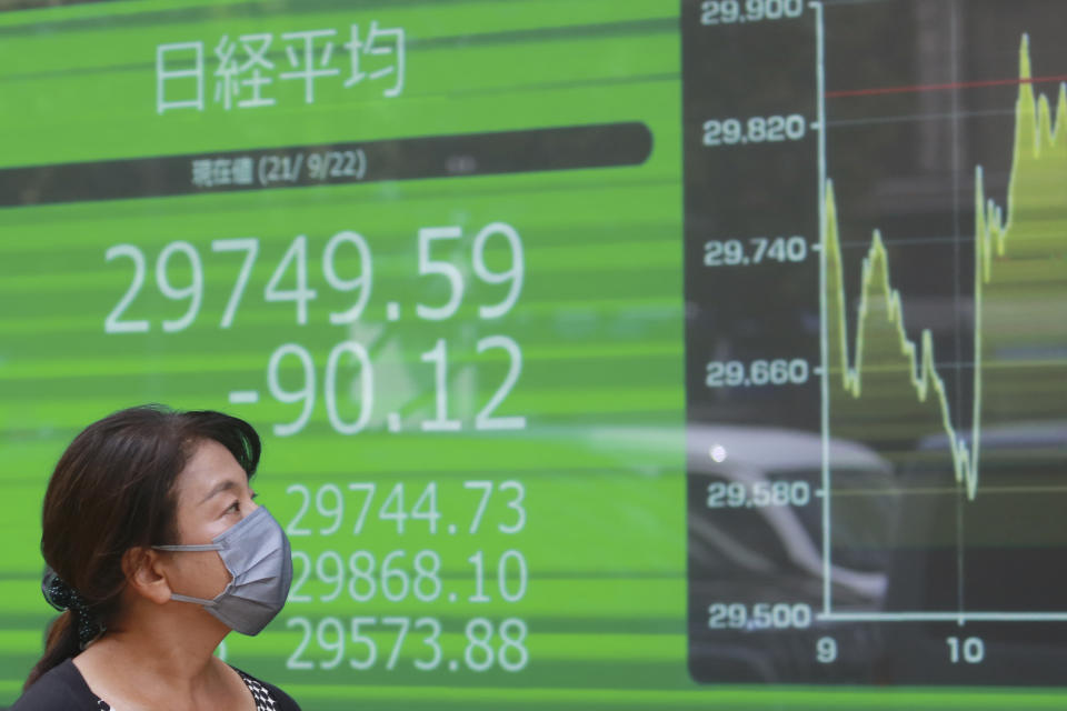 A woman walks by an electronic stock board of a securities firm in Tokyo, Wednesday, Sept. 22, 2021. Asian shares were mostly lower on Wednesday after major indexes ended mixed on Wall Street. (AP Photo/Koji Sasahara)