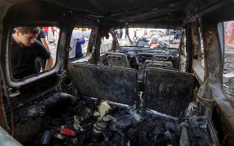 A Palestinian looks at a damaged vehicle in the aftermath of an Israeli air strike on a house, amid Israeli-Palestinian fighting, in Gaza City - Mohammed Salem /Mohammed Salem 