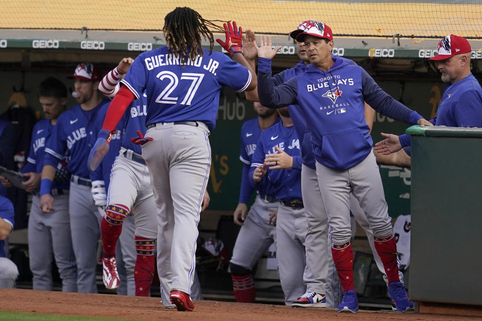 Toronto Blue Jays' Vladimir Guerrero Jr. (27) is congratulated by manager Charlie Montoyo, middle right, after scoring against the Oakland Athletics during the fourth inning of a baseball game in Oakland, Calif., Monday, July 4, 2022. (AP Photo/Jeff Chiu)