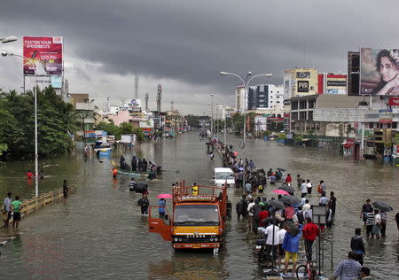 People stand on a flooded road in Chennai, December 2, 2015. REUTERS/Stringer