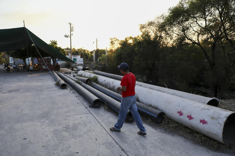 A man walks by pipes left on the ground after activists blocked the final meters construction of the thermo-electric plant pipeline in San Pedro Apatlaco, Morelos state, Mexico, Saturday, Feb. 22, 2020. The project has advanced in fits and starts for more than a decade. It's essentially complete, but legal stays have also prevented connection of the last mile of pipeline needed to fire up the power plant. (AP Photo/Eduardo Verdugo)