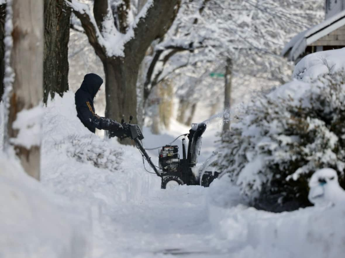 A person is seen using a snow blower on a driveway in Halifax. A nor'easter brought several centimetres of snow and high winds across the Maritimes. (Robert Short/CBC - image credit)