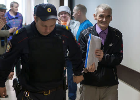 Historian Yuri Dmitriev accused of using his adopted daughter to produce child pornography, of illegally possessing a firearm, and of depravity, is escorted by police upon his arrival for a court hearing in Petrozavodsk, Russia, June 5, 2017. Picture taken June 5, 2017. REUTERS/Igor Podgorny