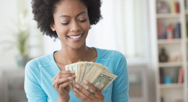 African American woman counting money in living room