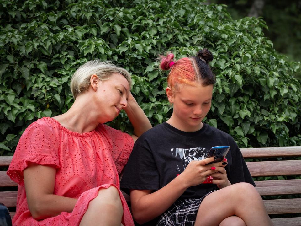 Teen girl holding mobile phone and looking at the screen.