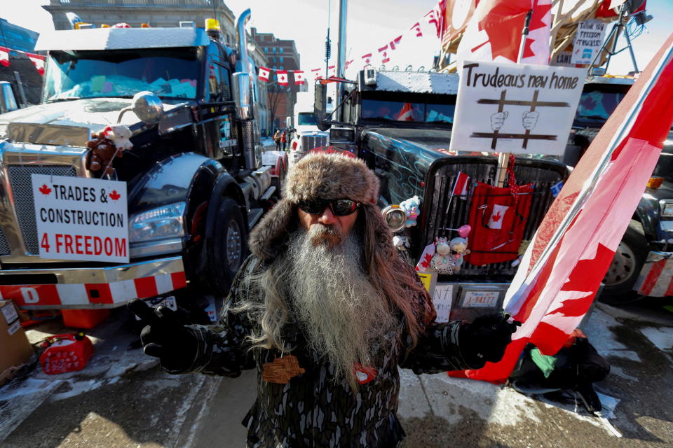 A person stands in front of trucks blocking Wellington Street as truckers and their supporters continue to protest against COVID vaccine mandates in Ottawa, Ontario, Canada, February 15, 2022. REUTERS/Patrick Doyle