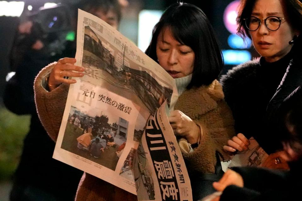 PHOTO: People read extra edition of Yomiuri Shimbun newspaper reporting the earthquakes Monday, Jan. 1, 2024 in Tokyo.  (Shuji Kajiyama/AP)