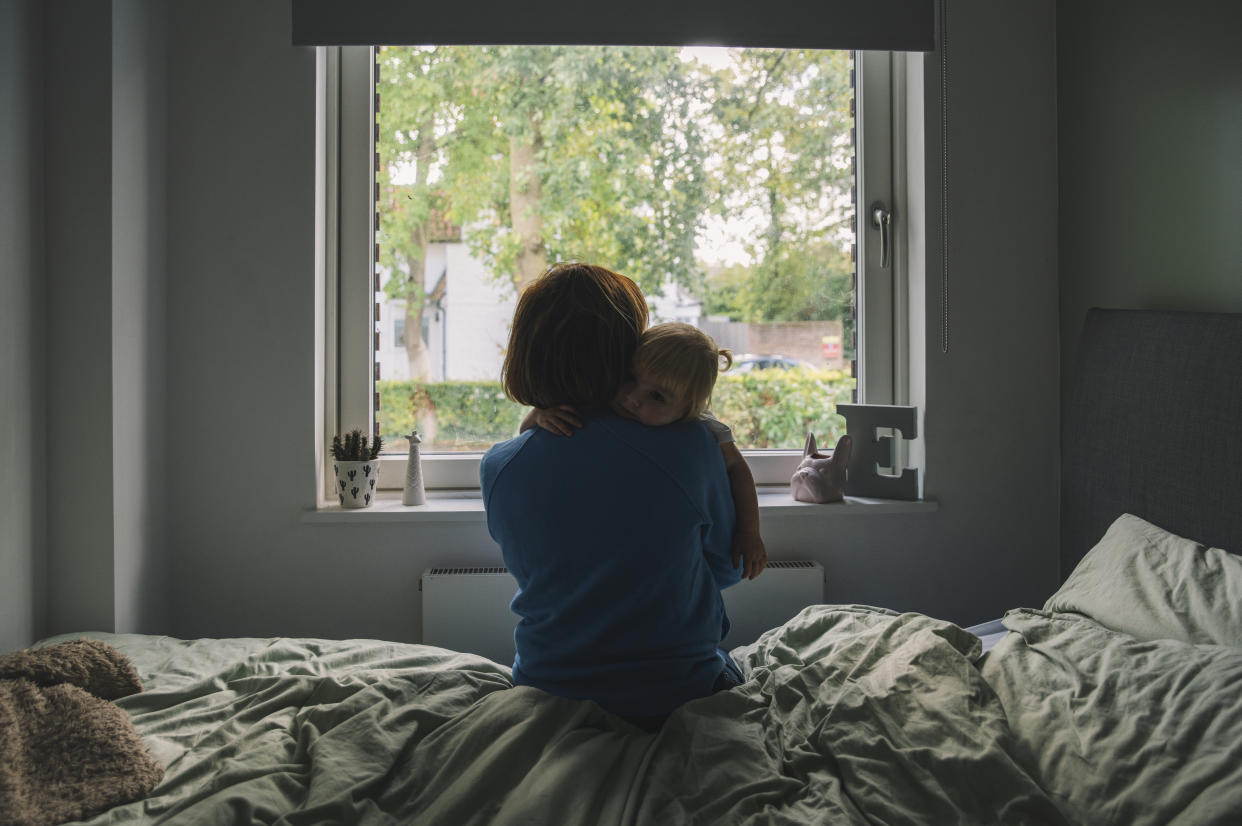 A mother embracing a young child while gazing out the window
