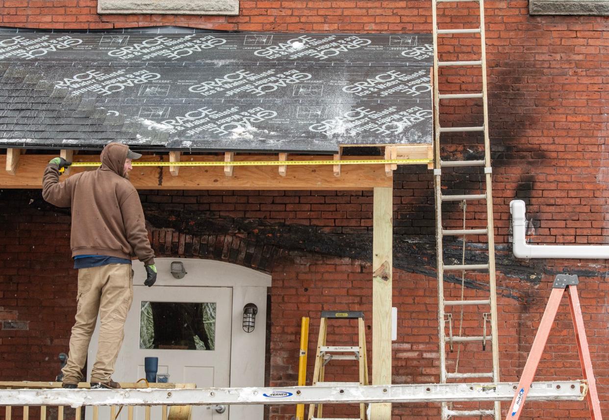 Neil Bates from Clukey Construction builds a porch roof on the Otter River Hotel in Templeton Tuesday. Damage from a September fire is seen on the brick wall.