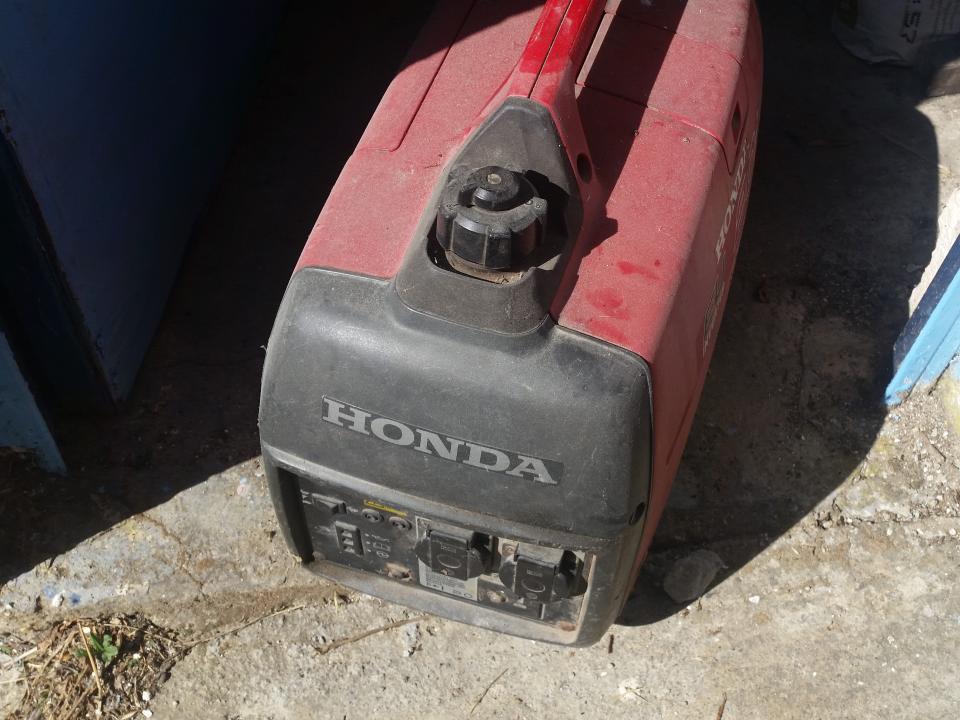 A red and black generator labeled Honda on a concrete floor.