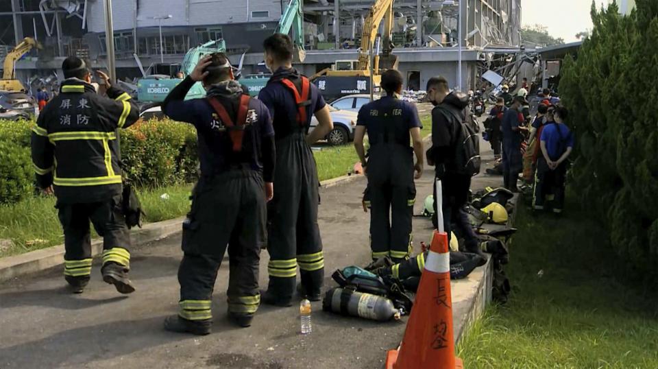 In this image made from video footage run by EBC, firefighters take rest near a burned factory of golf ball manufacturer Launch Technologies Co. in the southern county of Pingtung in Taiwan on Saturday, Sept. 23, 2023. The golf ball factory fire has left multiple people killed, and the victims include several firefighters, according to Taiwanese media reports. (EBC via AP)