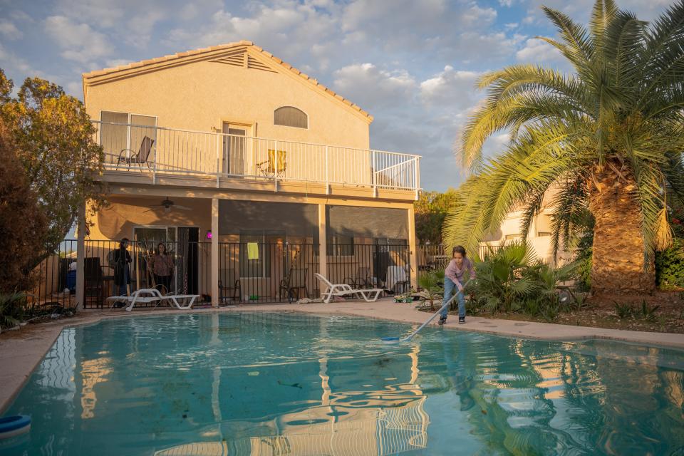 Alvira Arvizo skims leaves from the pool in the backyard of her temporary Avondale home on Nov. 18, 2022.