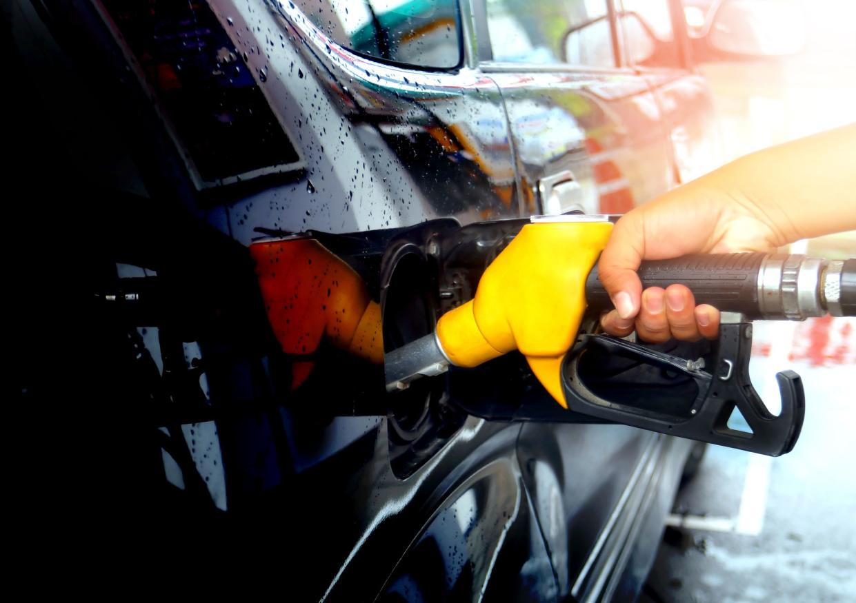 Hand refilling yellow fuel gasoline dispenser the car with fuel at the gasoline station energy crisis