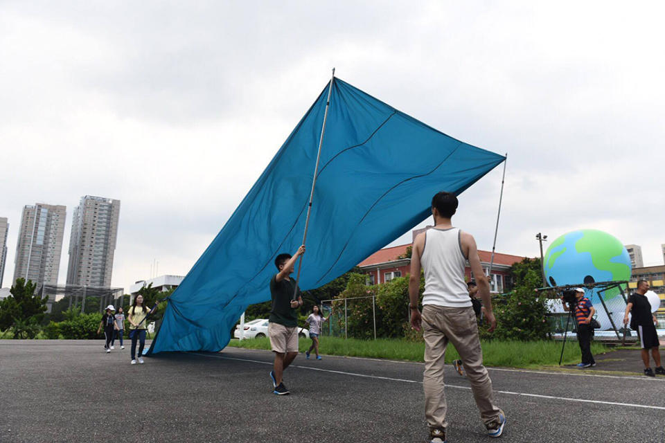 ▲世大運閉幕式彩排首度曝光，表演人員手持巨大藍色布條展演出台灣海洋島嶼意象，知名樂團滅火器則將搭上有滿載祝福象徵的傳統彩繪船隻，歡送各國選手。（圖／臺北市政府提供）