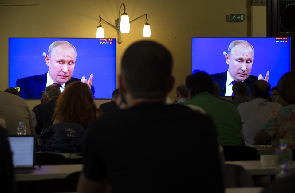 Journalists look at screens showing Russian President Vladimir Putin as he answers a question during his annual call-in show in Moscow, Russia, Thursday, June 20, 2019. Putin hosts call-in shows every year, which typically provides a platform for ordinary Russians to appeal to the president on issues ranging from foreign policy to housing and utilities. (AP Photo/Alexander Zemlianichenko)