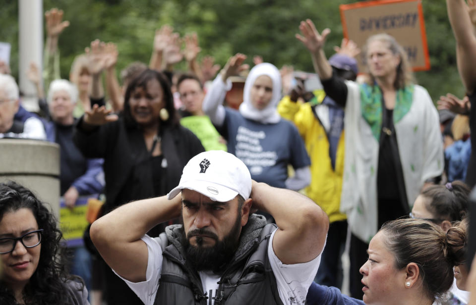 Jose Robles rests with his hands behind his head as supporters hold their arms toward him during a blessing before he presented himself to U.S. Immigration and Customs Enforcement officials Wednesday, July 17, 2019, in Tukwila, Wash. Robles, who has spent the past year inside a Seattle church to avoid being deported to Mexico, has been detained. The arrest Wednesday prompted protests from a crowd of supporters who had accompanied Robles to the agency. His deportation has temporarily been put on hold by a federal appeals court, and he has a pending visa application. (AP Photo/Elaine Thompson)