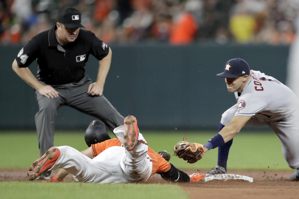 Baltimore Orioles' Chris Davis, left, slides in under the tag of Houston Astros shortstop Carlos Correa with a double as second base umpire Mike Everitt watches during the sixth inning of a baseball game, Saturday, Aug. 10, 2019, in Baltimore. (AP Photo/Julio Cortez)