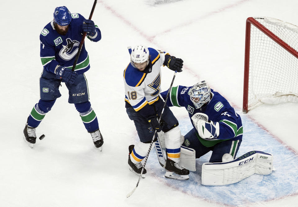 Vancouver Canucks goalie Jacob Markstrom (25) makes a save as St. Louis Blues' Robert Thomas (18) and Canucks' Jordie Benn (4) battle during second-period NHL Western Conference Stanley Cup playoff hockey game action in Edmonton, Alberta, Friday, Aug. 21, 2020. (Jason Franson/The Canadian Press via AP)