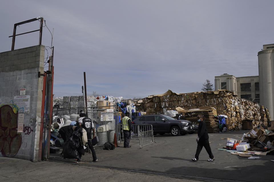 People walk inside a recycling location in Oakland, Calif., Thursday, Feb. 18, 2021. Disadvantaged communities in America are disproportionately affected by pollution from industry or waste disposal, but their complaints have few outlets and often reach a dead end. (AP Photo/Jeff Chiu)