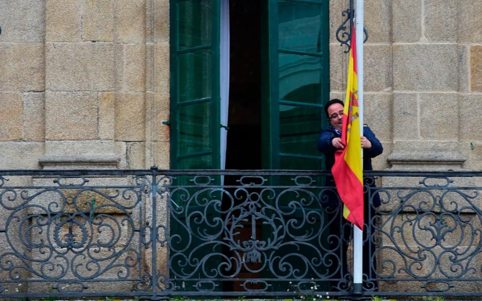 An employee sets the Spanish flag at half mast on a balcony of the council of Betanzos - Credit: MIGUEL RIOPA/AFP