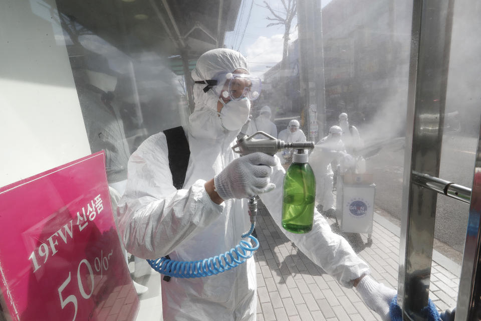 Un operario equipado con un equipo de protección rocía desinfectante en una estructura como medida de precaución contra el coronavirus, en una calle comercial de Seúl, Corea del Sur, el 27 de febrero de 2020. (AP Foto/Ahn Young-joon)
