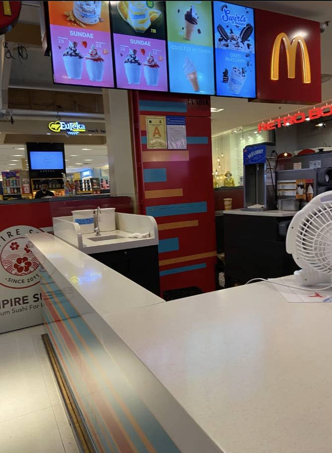 Counter and seating area of a fast-food restaurant with menu displays, and a health grade rating visible