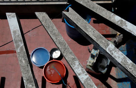 Buckets filled with water stand next to a washing machine on the roof of an apartment block in Caracas, Venezuela, March 17, 2019. REUTERS/Carlos Jasso