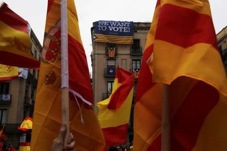 A big banner reading "We want to vote" hangs from a building next to Esteladas (Catalan separatist flag) as people hold up Spanish flags during a demonstration in favor of a unified Spain a day before the banned October 1 independence referendum, in Barcelona, Spain, September 30, 2017. REUTERS/Susana Vera