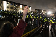 A demonstrator raises their hand while facing off against a perimeter of police as they defy an order to disperse during a protest against the police shooting of Daunte Wright, late Monday, April 12, 2021, in Brooklyn Center, Minn. (AP Photo/John Minchillo)