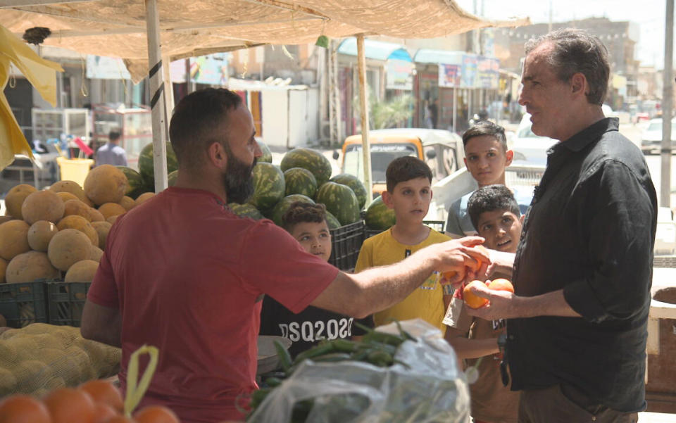 This image released by ABC News Studios shows Bob Woodruff, right, in the marketplace in Sabaa Al Bour, Iraq. Woodruff has returned to the Iraqi roadside where a bomb nearly killed him while on assignment for ABC News in 2006. “After the Blast: The Will to Survive,” which airs on ABC Friday at 8 p.m. Eastern and begins streaming on Hulu a day later. (ABC News Studios via AP)