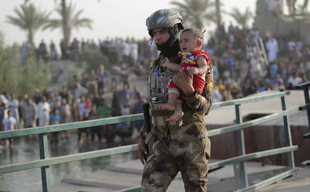 An Iraqi soldier carries a displaced kid from Ramadi on the outskirts of Baghdad, May 19, 2015. REUTERS/Stringer