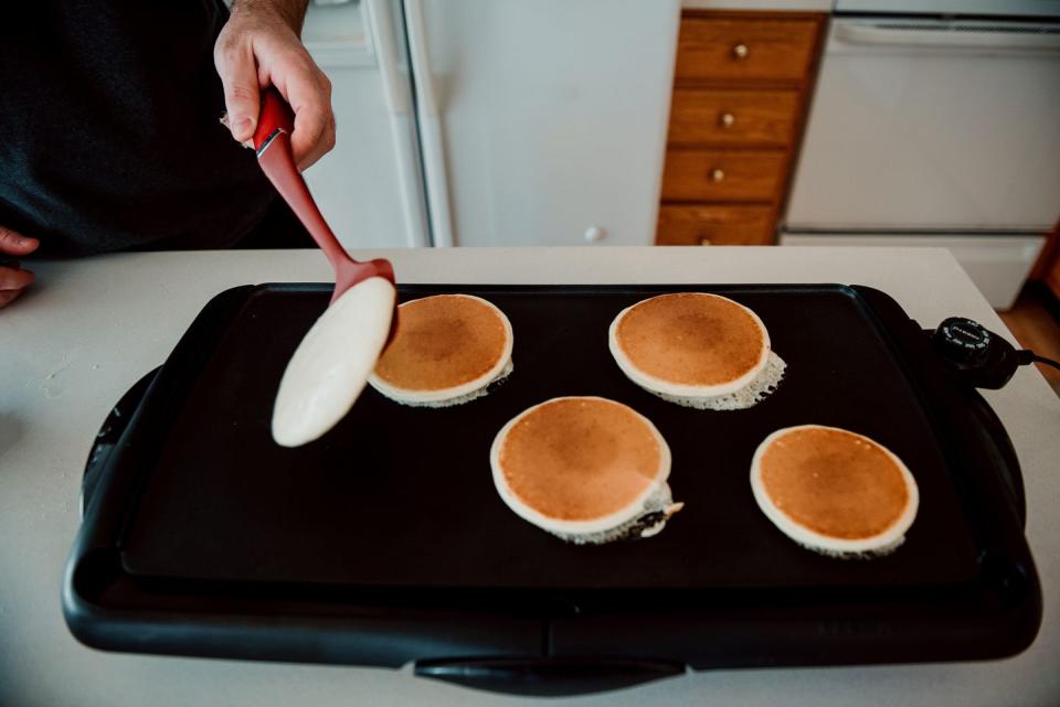 father flipping pancakes on a griddle