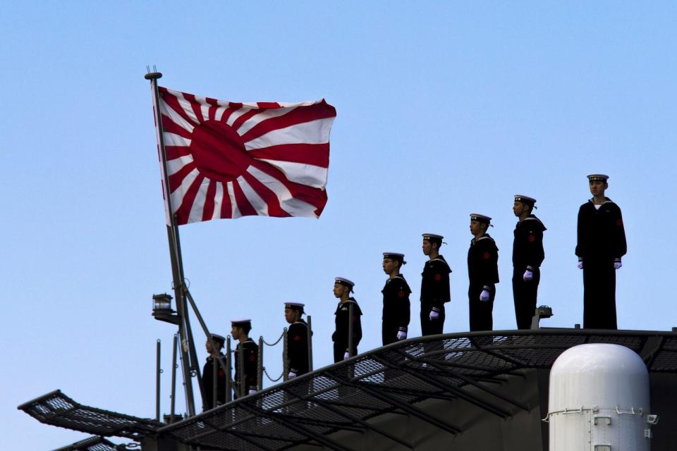 Sailors stand on the deck of the Izumo warship as it departs from the harbour of the Japan United Marine shipyard in Yokohama, south of Tokyo March 25, 2015.