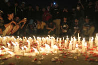 Indonesian soccer fans light candles during a vigil for the victims of Saturday's soccer riots, in Jakarta, Indonesia, Sunday, Oct. 2, 2022. Panic and a chaotic run for exits after police fired tear gas at an Indonesian soccer match in East Java to drive away fans upset with their team's loss left a large number of people dead, most of whom were trampled upon or suffocated. (AP Photo/Dita Alangkara)