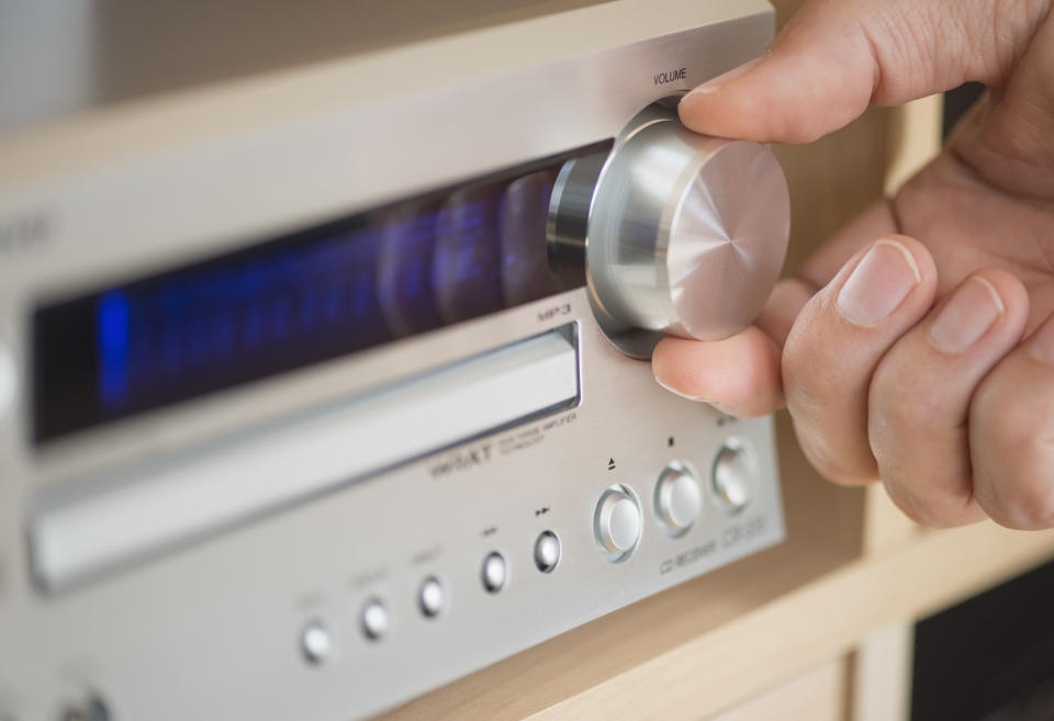 Person adjusting the volume on a home stereo amplifier