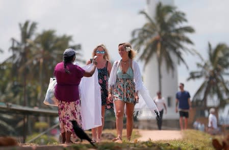 A local vendor tries to sell handmade items to tourists at Dutch Fort in Galle