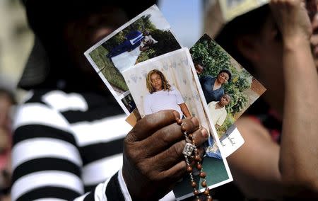 A faithful holds pictures of her relatives as she attends a mass lead by Pope Francis during a two-day pastoral visit in Turin, Italy, June 21, 2015. REUTERS/Giorgio Perottino