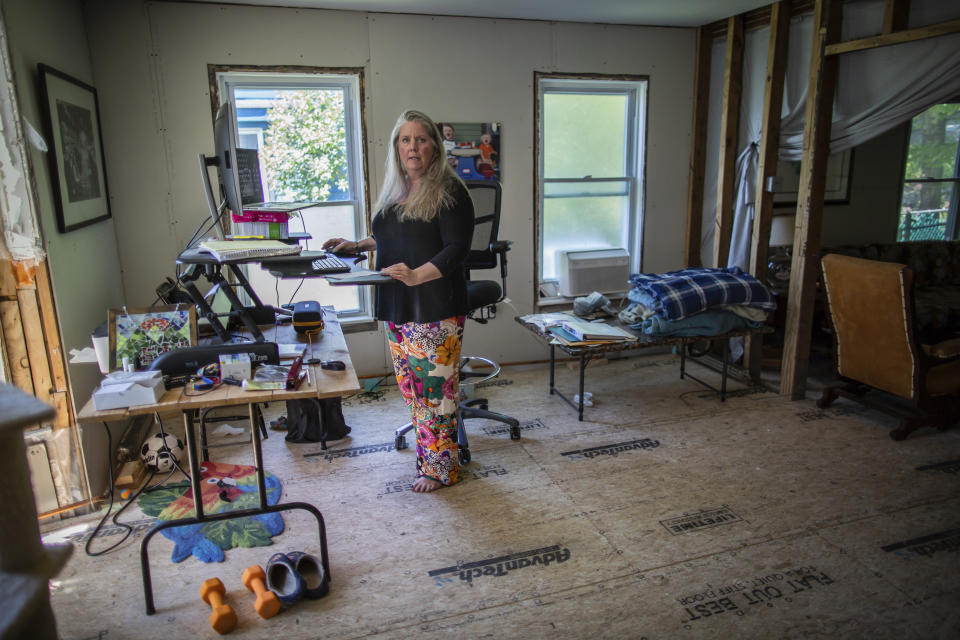 Lisa Edson Neveu, 52, works at the main room of her house in Montpelier, Vt., July 3, 2024 that was damaged by the 2023. A year after catastrophic flooding inundated parts of Vermont, some homeowners are still in the throes of recovery. (AP Photo/ Dmitry Belyakov)