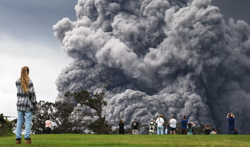 People watch at a golf course as an ash plume rises in the distance from the Kilauea volcano on Hawaii's Big Island in Hawaii Volcanoes National Park.&nbsp;