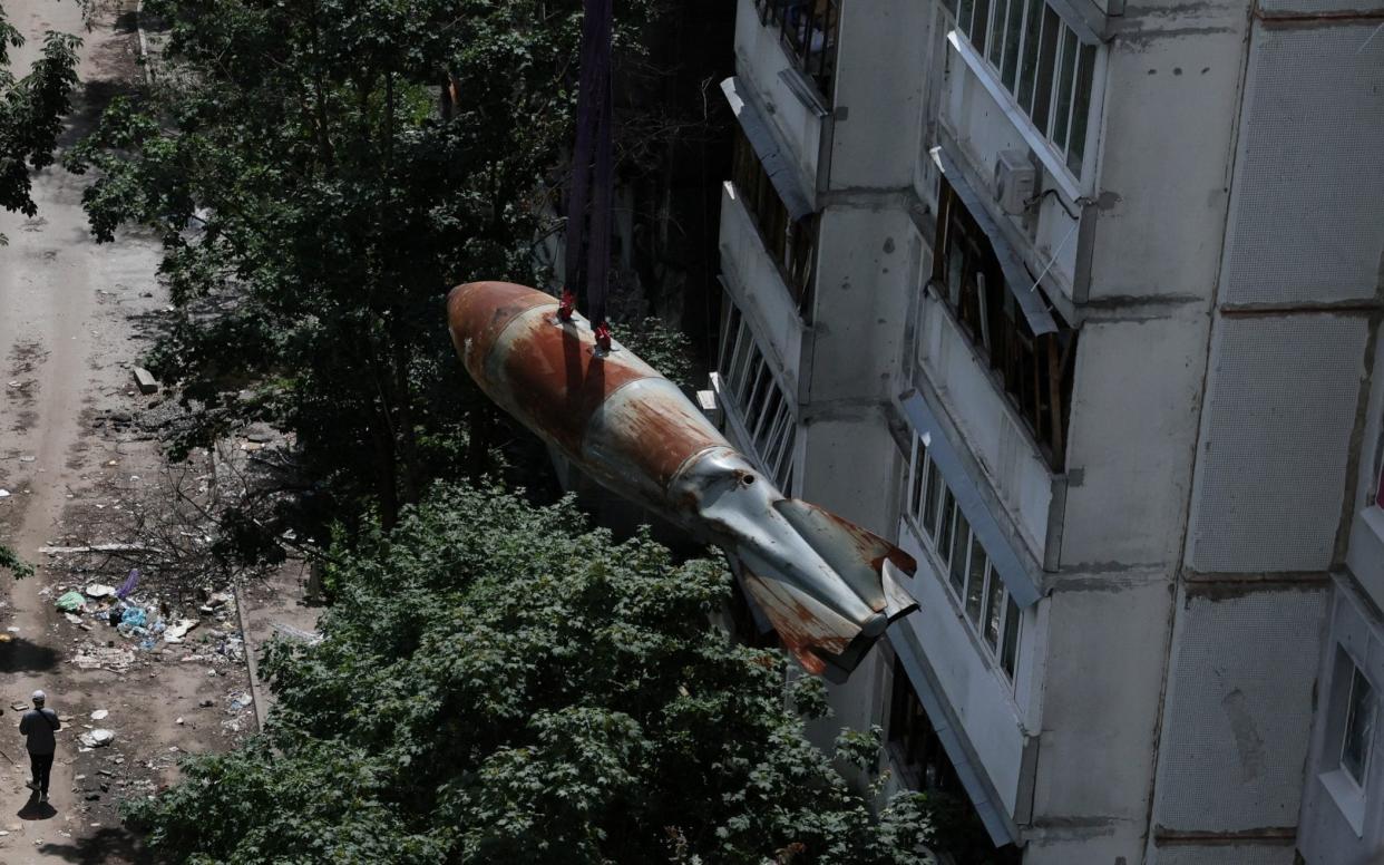 A 500kg bomb that failed to detonate when it landed on an apartment building in Kharkiv in March and was later defused is lowered to the ground. However, Russian attacks continue