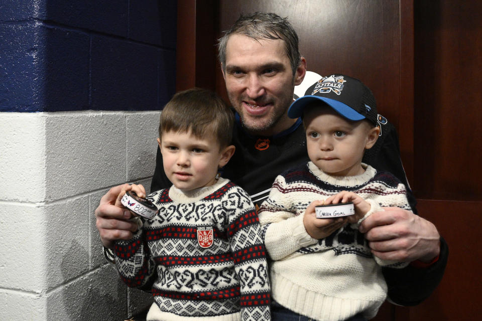 Washington Capitals left wing Alex Ovechkin, center, poses with his children Sergei, left, and Ilya, right, and the pucks he scored goals 801 and 802 after an NHL hockey game against the Winnipeg Jets, Friday, Dec. 23, 2022, in Washington. (AP Photo/Nick Wass)